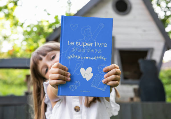 L'enfant tient le livre de souvenirs de son papa, rempli de moments précieux et de conseils